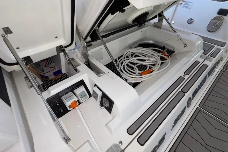 Slide: The Image of 2023 Monterey 385SS Super Sport boat storage compartment with coiled hose and electrical connections. - 28