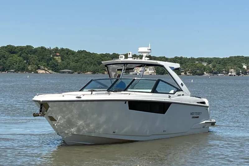 Slide: The Image of 2023 Monterey 385SS Super Sport boat on a serene lake with lush green shoreline. - 4