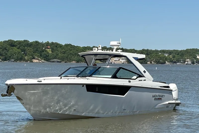 Slide: The Image of 2023 Monterey 385SS Super Sport boat on a calm lake with lush green shoreline. - 5