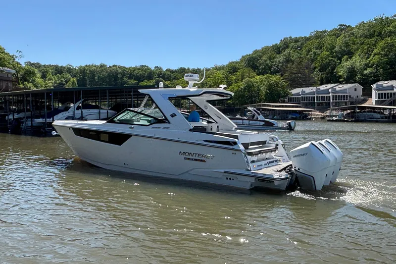 Slide: The Image of 2023 Monterey 385SS Super Sport boat on a lake, surrounded by docks and trees. - 7