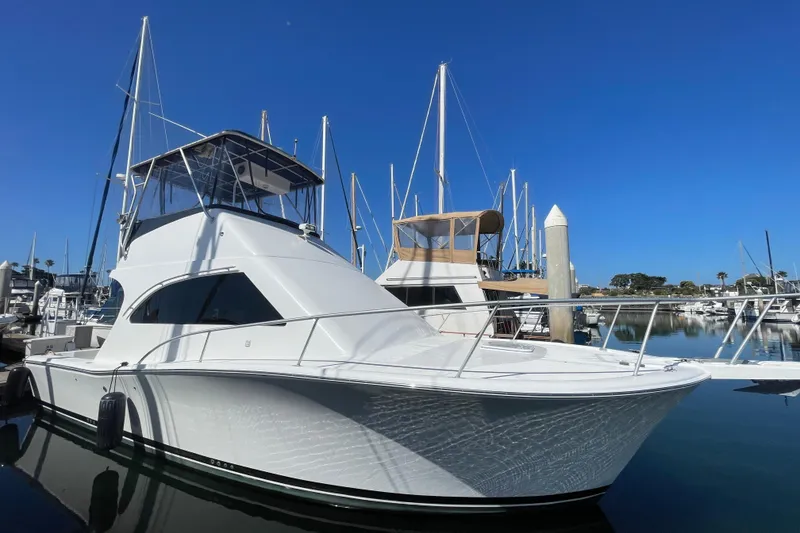 The Image of 2003 Luhrs 34 Convertible yacht docked in a marina under clear blue skies. - 0