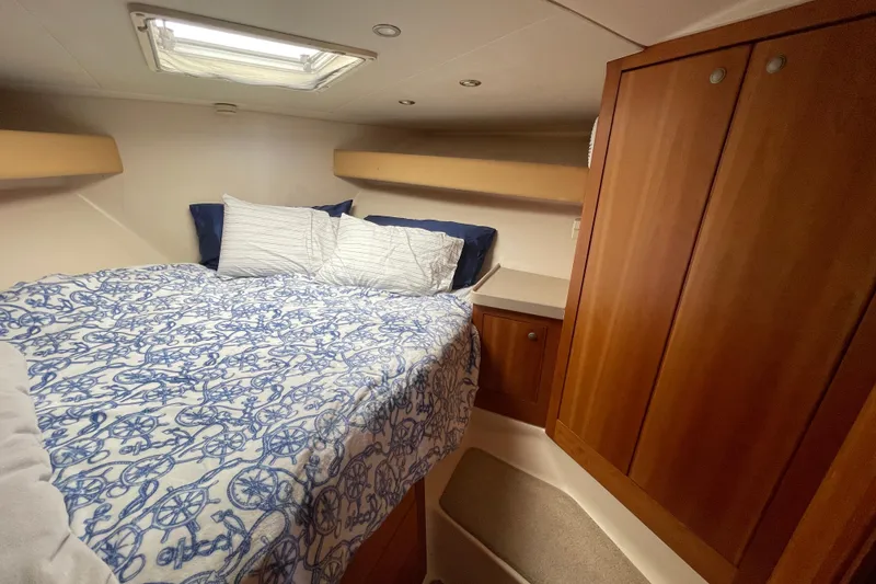 Slide: The Image of Cozy cabin interior of 2003 Luhrs 34 Convertible with nautical-themed bedding and wooden cabinetry. - 31