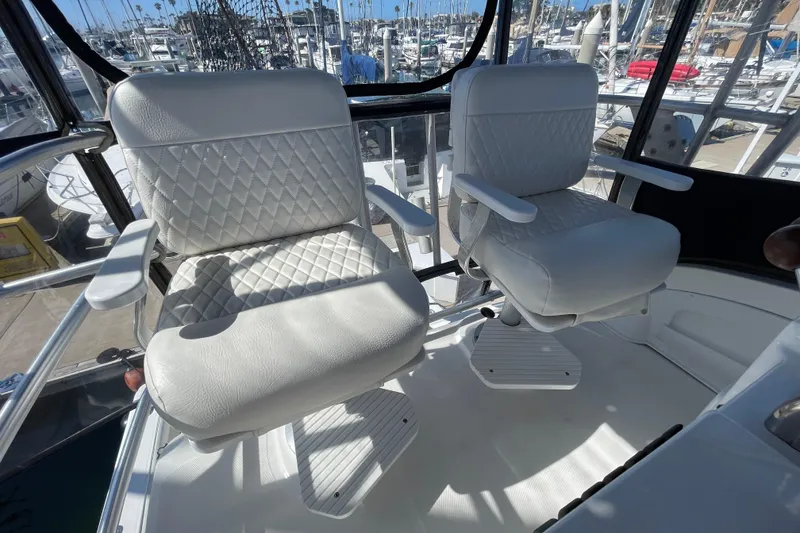 Slide: The Image of White captain chairs on 2003 Luhrs 34 Convertible boat, marina background. - 36
