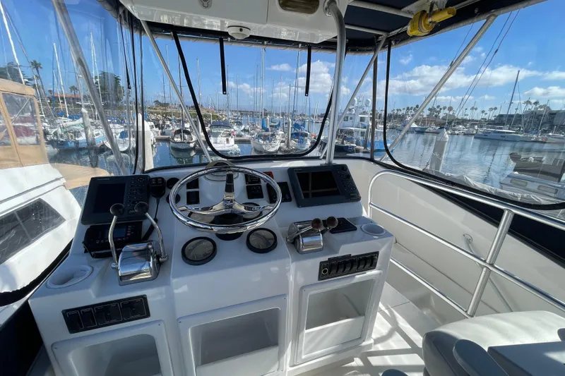Slide: The Image of 2003 Luhrs 34 Convertible helm with marina view, featuring modern controls and navigation equipment. - 37