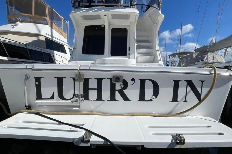 Slide: The Image of 2003 Luhrs 34 Convertible boat docked, featuring "LUHR'D IN" on the stern. - 4