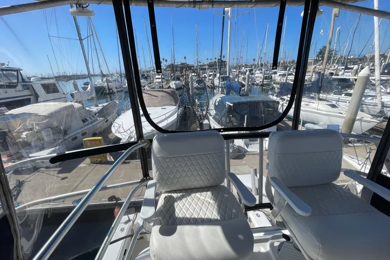 Slide: The Image of 2003 Luhrs 34 Convertible yacht interior with marina view, featuring white seating and clear windows. - 50