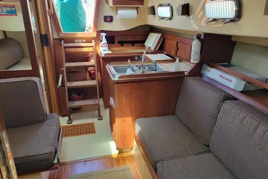 Slide: The Image of 1988 Island Packet 31 sailboat interior with wood finish, kitchenette, and seating area. - 20