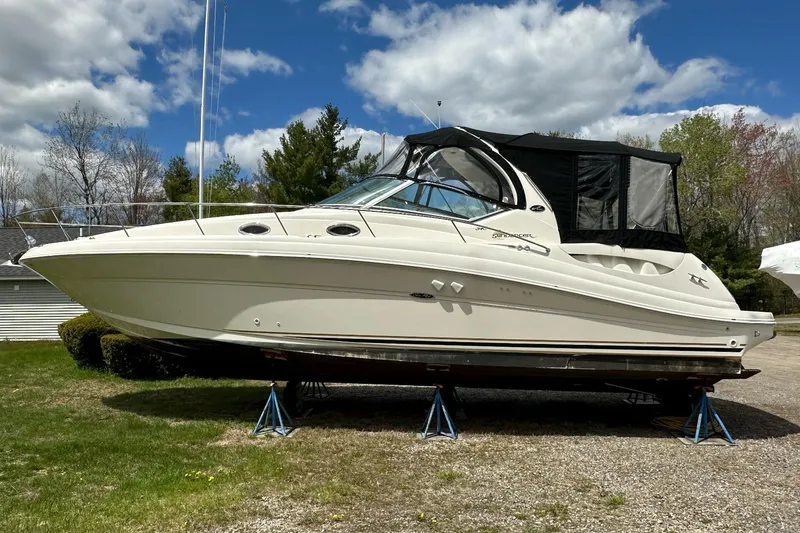 The Image of 2003 Sea Ray 340 Sundancer boat on stands, outdoors under a partly cloudy sky. - 0