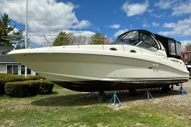Slide: The Image of 2003 Sea Ray 340 Sundancer boat on stands, outdoors under a partly cloudy sky. - 2