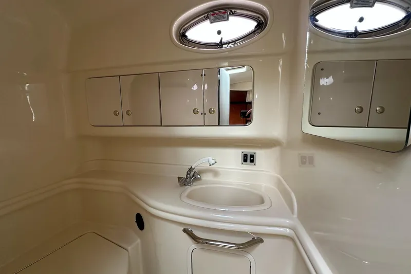 Slide: The Image of 2003 Sea Ray 340 Sundancer bathroom with sink, cabinets, and oval windows. - 21