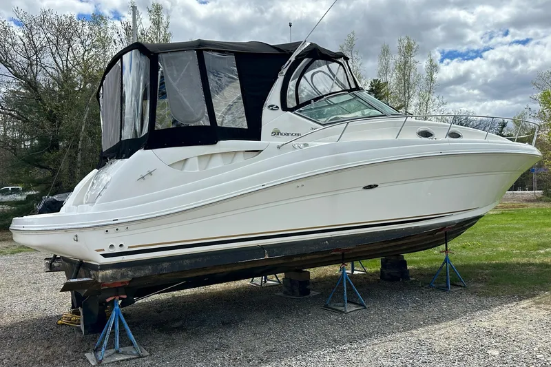 Slide: The Image of 2003 Sea Ray 340 Sundancer boat on stands, outdoors, under cloudy sky. - 3