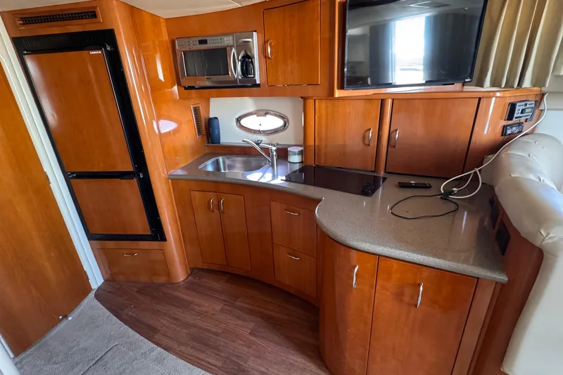 Slide: The Image of 2006 Carver 36 Mariner yacht interior with kitchenette, featuring wood cabinetry and modern appliances. - 9