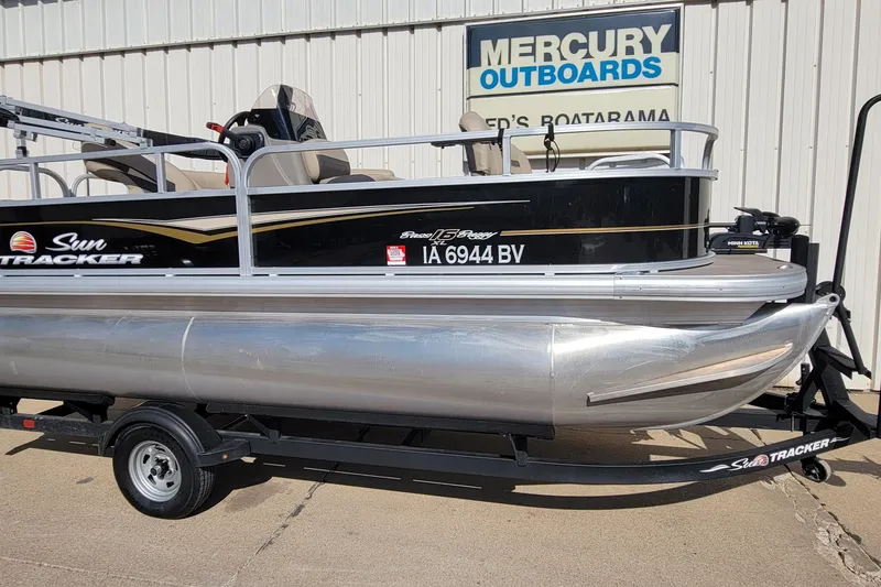 Slide: The Image of 2022 SUNTRACKER BASS BUGGY 16 XLS pontoon boat on trailer, parked outside Mercury Outboards. - 4