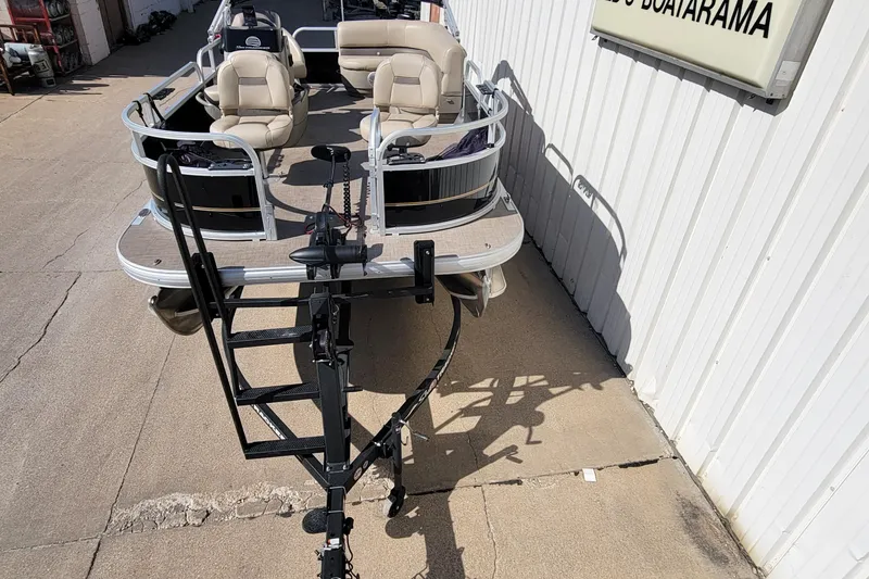 Slide: The Image of 2022 SUNTRACKER BASS BUGGY 16 XLS pontoon boat on trailer, parked beside building. - 6