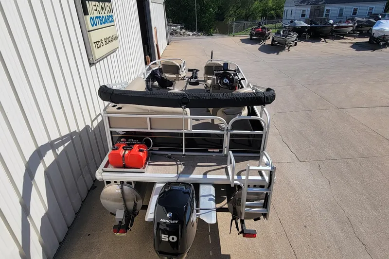 Slide: The Image of 2022 SUNTRACKER BASS BUGGY 16 XLS pontoon boat with Mercury outboard motor, parked outdoors. - 8