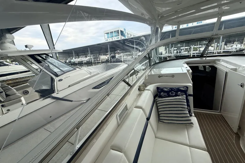 Slide: The Image of 2016 Intrepid 430 Sport Yacht interior with white seating and striped cushions at marina. - 18