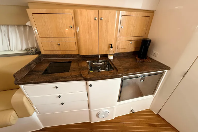 Slide: The Image of Compact kitchen area in a 2016 Intrepid 430 Sport Yacht with wooden cabinets and modern appliances. - 8