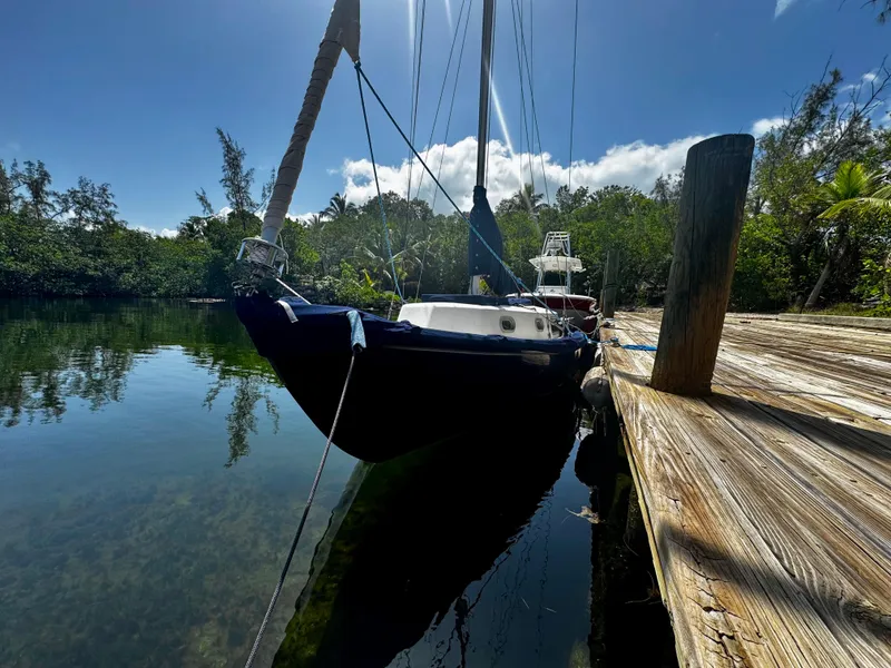 Slide: The Image of Vintage 1968 Sailboat 24 docked on calm water, surrounded by lush greenery. - 2