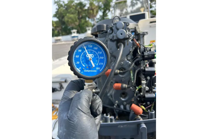 Slide: The Image of Gloved hand holding compression gauge near boat engine, Scout 172 Sportfish 2001. - 32