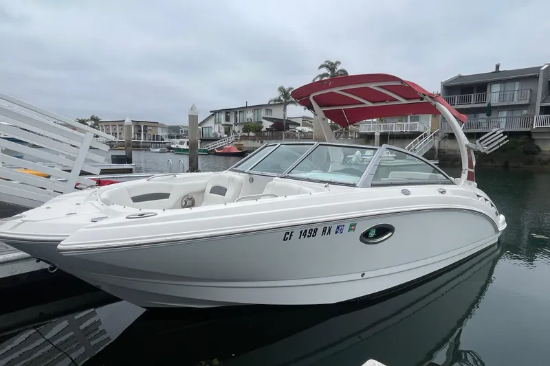 The Image of 2014 Chaparral 224 Sunesta boat docked in a marina with red canopy. - 0