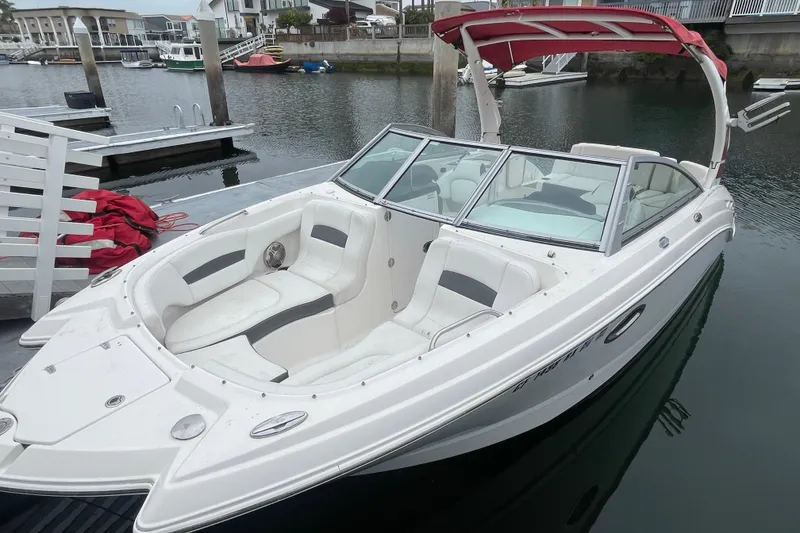 Slide: The Image of 2014 Chaparral 224 Sunesta boat docked in a marina, featuring spacious seating and sleek design. - 1