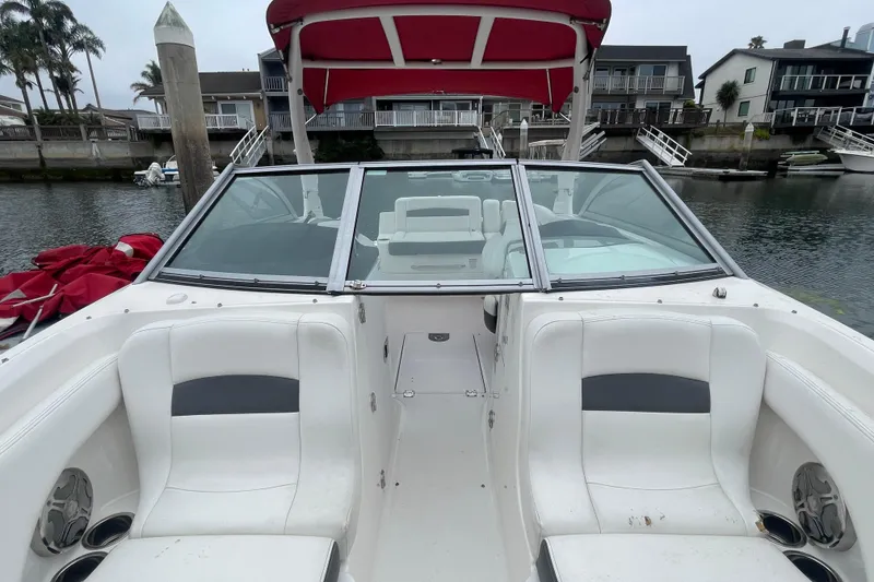 Slide: The Image of 2014 Chaparral 224 Sunesta boat with white seating and red canopy in a marina. - 12