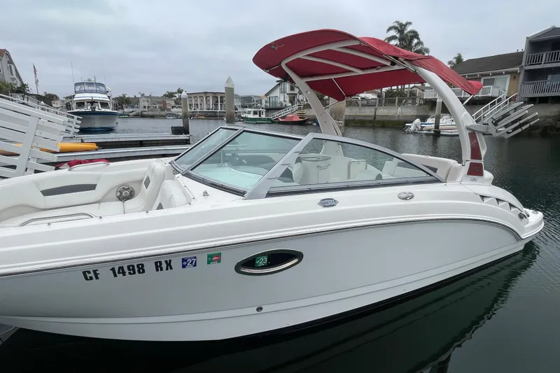 Slide: The Image of 2014 Chaparral 224 Sunesta boat docked in a marina with red canopy. - 2