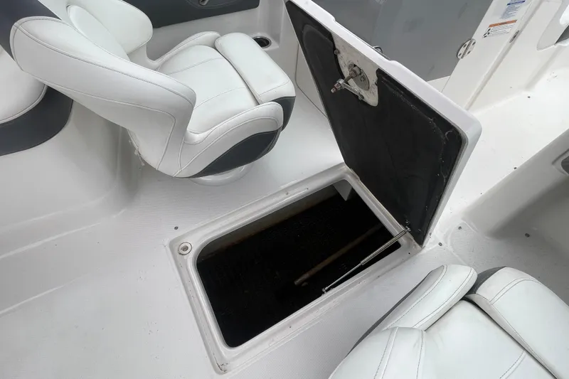 Slide: The Image of 2014 Chaparral 224 Sunesta boat interior with open storage compartment and white seating. - 21
