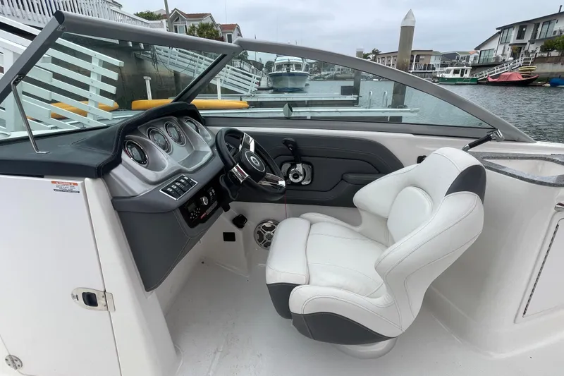 Slide: The Image of 2014 Chaparral 224 Sunesta boat cockpit with steering wheel and white captain's chair. - 23