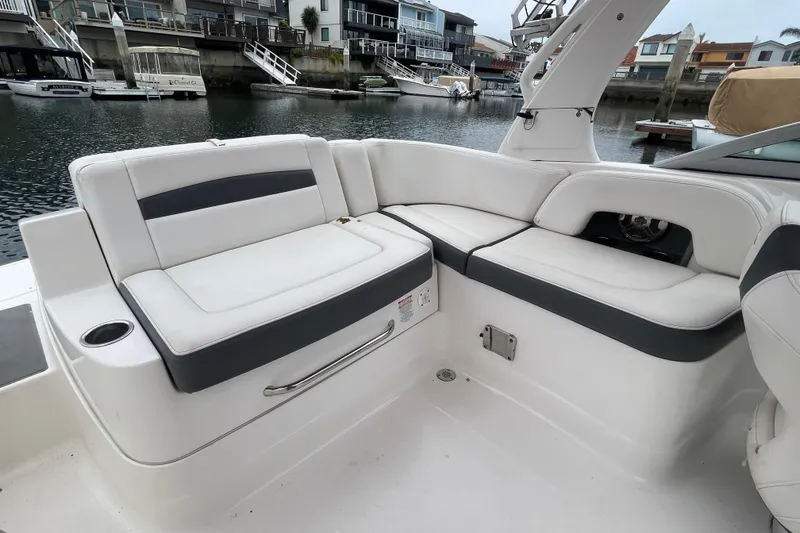 Slide: The Image of 2014 Chaparral 224 Sunesta boat interior with white seating, docked in a marina. - 32