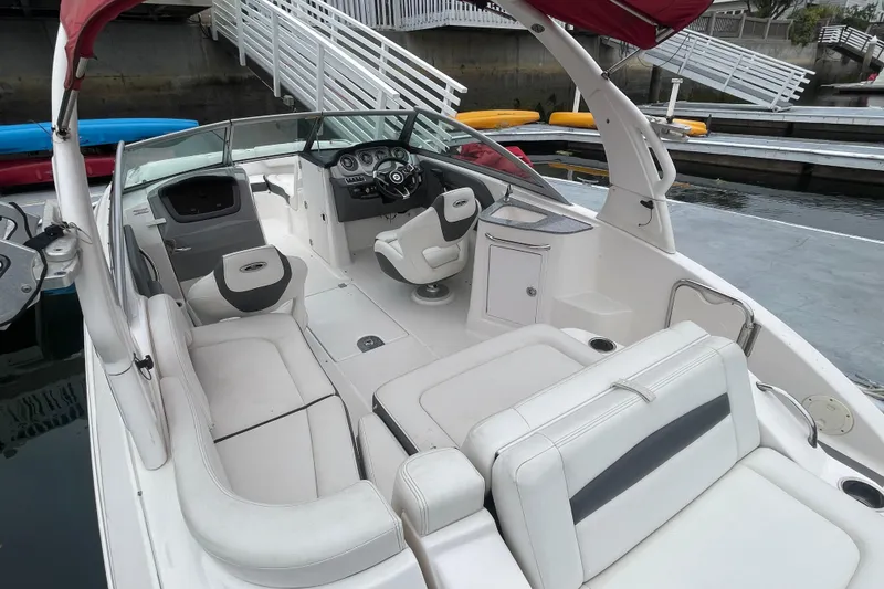 Slide: The Image of 2014 Chaparral 224 Sunesta boat interior with white seating and helm at dock. - 33