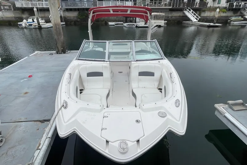 Slide: The Image of 2014 Chaparral 224 Sunesta boat docked, featuring spacious seating and a red canopy. - 5