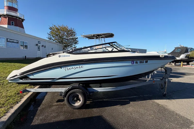 The Image of 2019 Yamaha SX190 boat on trailer, parked near a lighthouse and building. - 1