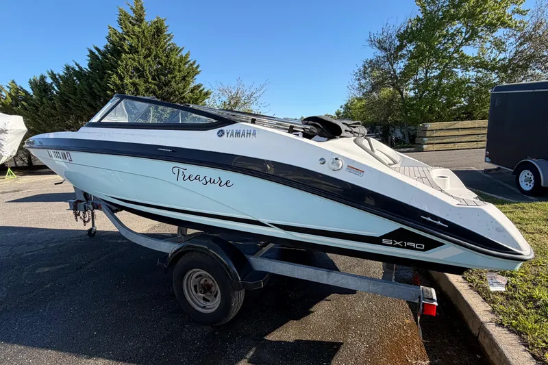 Slide: The Image of 2019 Yamaha Boats SX190 on trailer, labeled "Treasure," parked outdoors. - 4