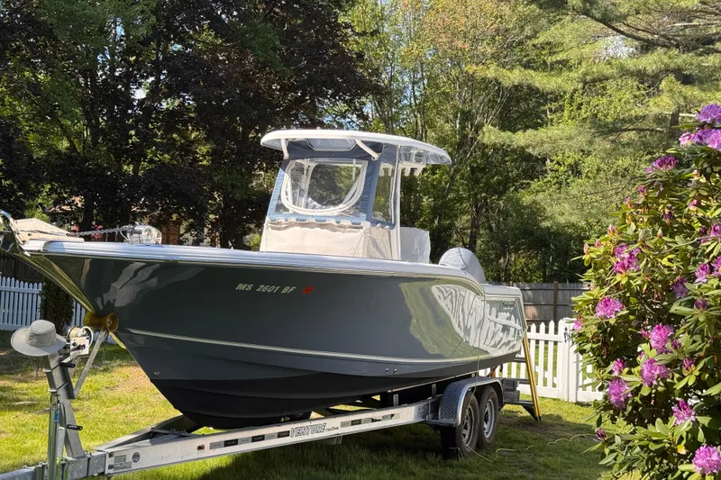Slide: The Image of 2015 Tidewater 252 CC Adventure boat on trailer, surrounded by lush greenery and flowers. - 2