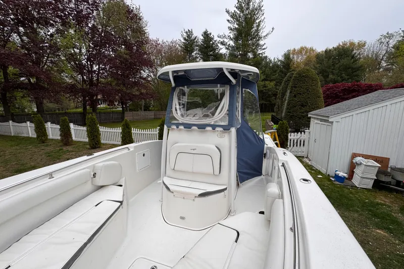 Slide: The Image of 2015 Tidewater 252 CC Adventure boat with white seating and blue canopy, parked outdoors. - 20
