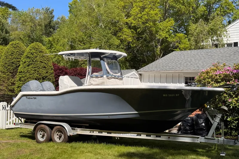 Slide: The Image of 2015 Tidewater 252 CC Adventure boat on trailer, parked in a lush garden setting. - 3