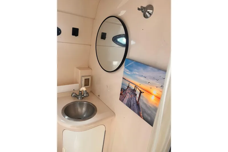 Slide: The Image of Bathroom interior of 2006 Regal Commodore 2665 with sink, mirror, and sunset artwork. - 11
