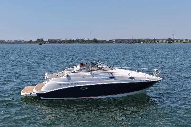 Slide: The Image of 2006 Regal Commodore 2665 boat cruising on a calm lake under a clear blue sky. - 2