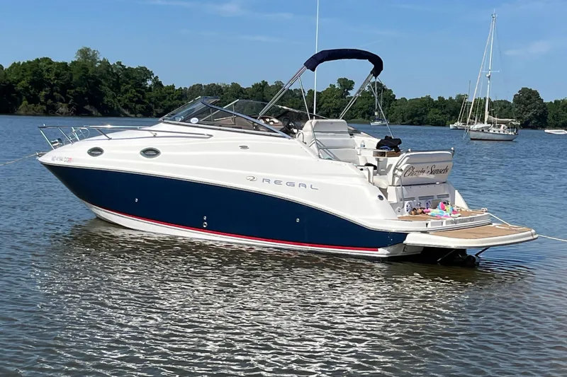 The Image of 2006 Regal Commodore 2665 boat anchored on a calm lake with trees in the background. - 4