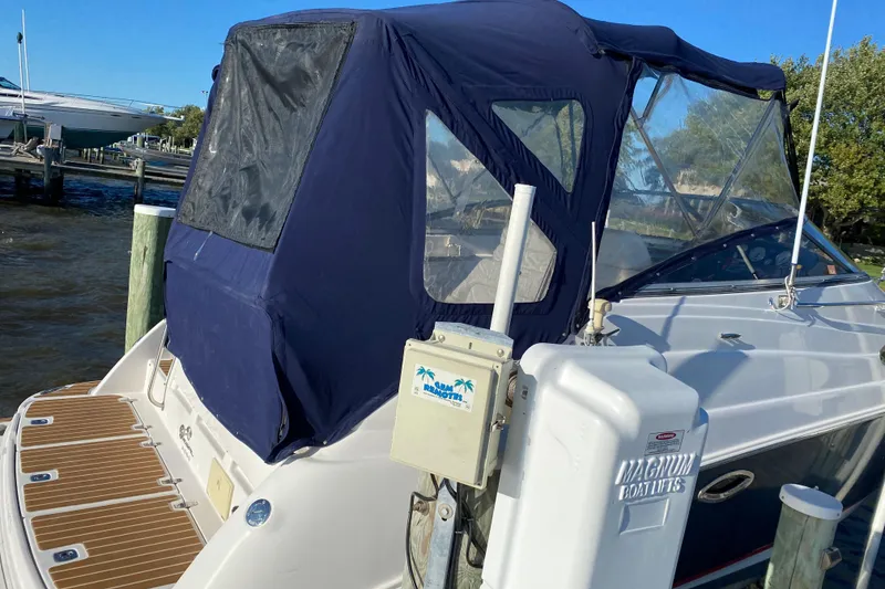 Slide: The Image of 2006 Regal Commodore 2665 boat docked with blue canopy and wooden deck. - 6