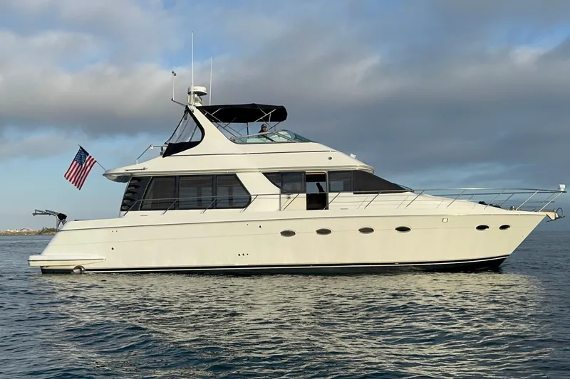 Slide: The Image of 2000 Carver 530 Voyager Pilothouse yacht on calm water, displaying an American flag. - 11