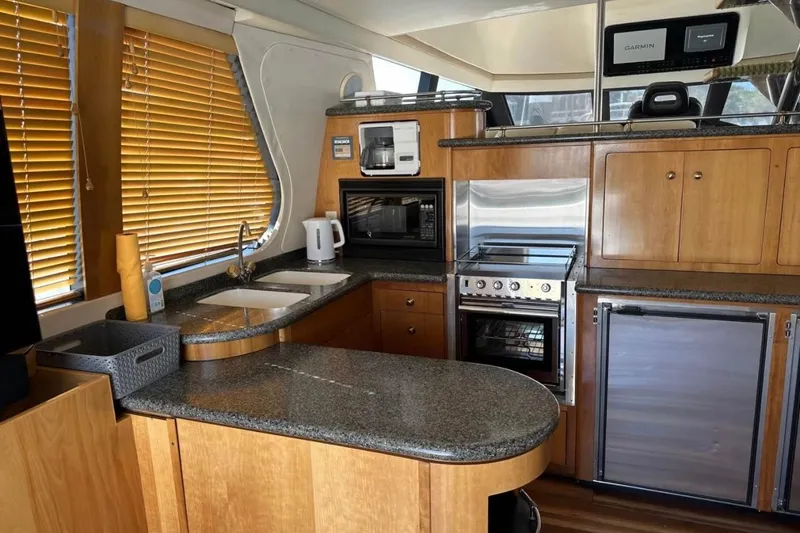 Slide: The Image of Interior of 2000 Carver 530 Voyager Pilothouse yacht kitchen with modern appliances and wood cabinetry. - 16