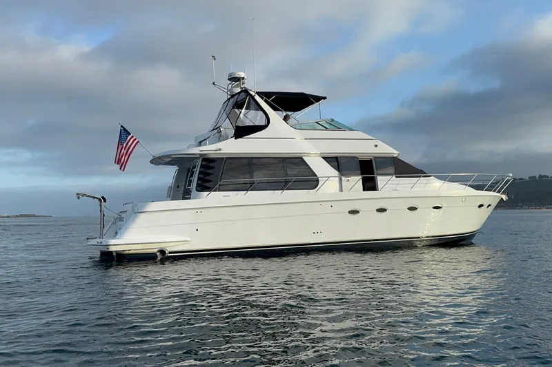 Slide: The Image of 2000 Carver 530 Voyager Pilothouse yacht on calm water, displaying an American flag. - 2