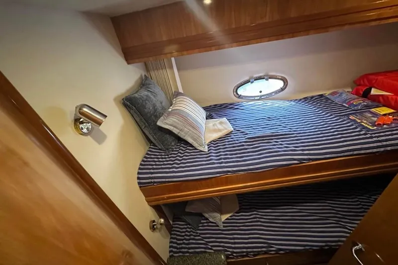 Slide: The Image of Cozy cabin interior of 2000 Carver 530 Voyager Pilothouse with striped bedding and porthole window. - 23