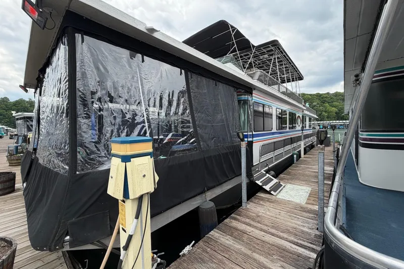 The Image of 1988 STARDUST 16x70 houseboat docked with covered deck and utility connections. - 0
