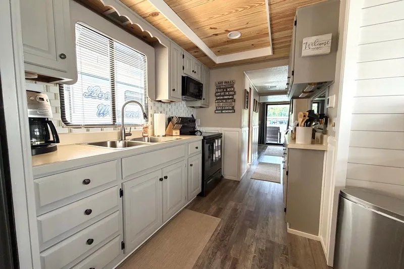 Slide: The Image of Modern kitchen interior in a 1988 STARDUST 16x70 houseboat, featuring wood accents and sleek appliances. - 16