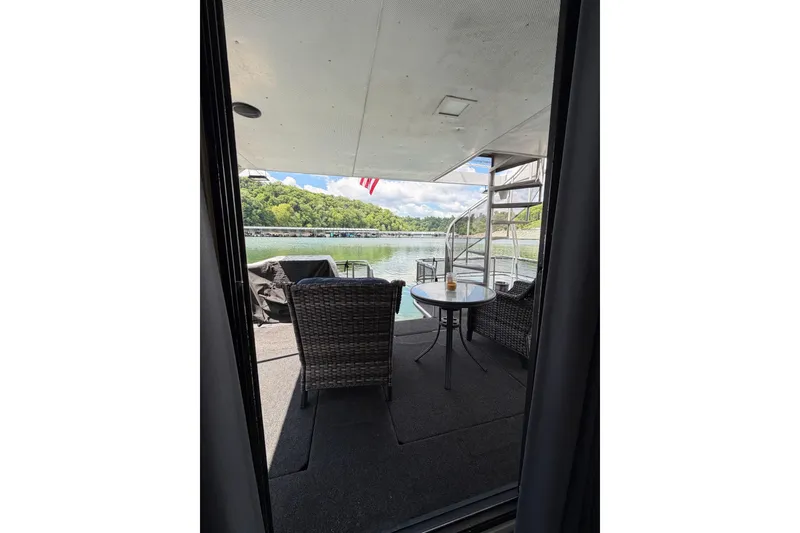 Slide: The Image of Outdoor seating on a 1988 STARDUST 16x70 houseboat overlooking a serene lake. - 33