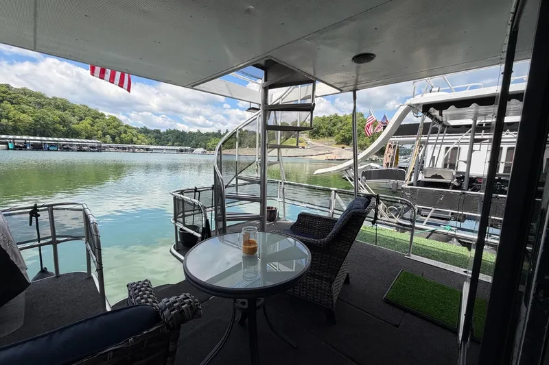 Slide: The Image of Houseboat deck view with seating, overlooking serene lake and docked boats, STARDUST 16x70, 1988. - 34