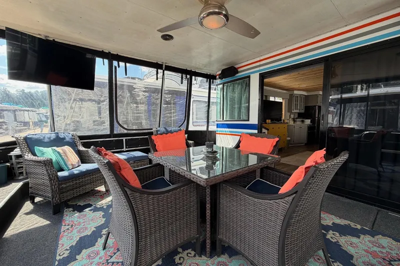 Slide: The Image of Houseboat interior with wicker furniture, glass table, and colorful cushions, featuring a ceiling fan and TV. - 4